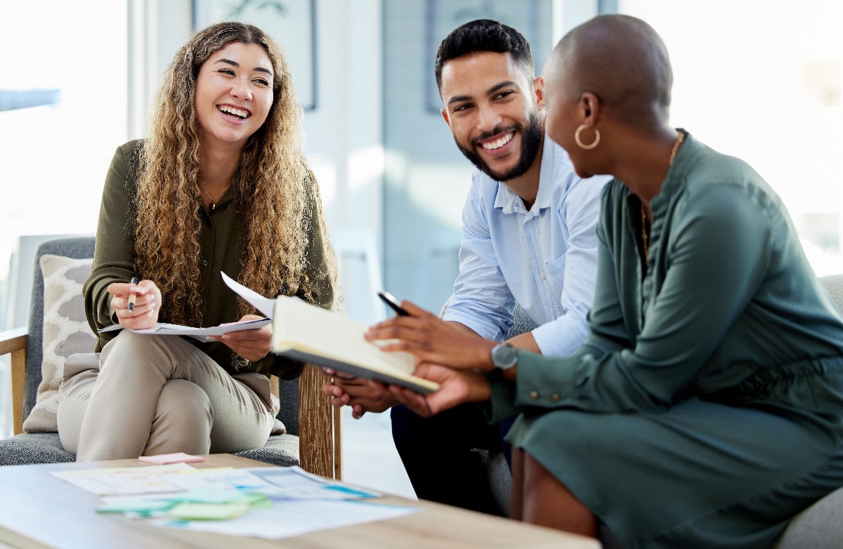 Three diverse business people laughing while having a casual meeting. 