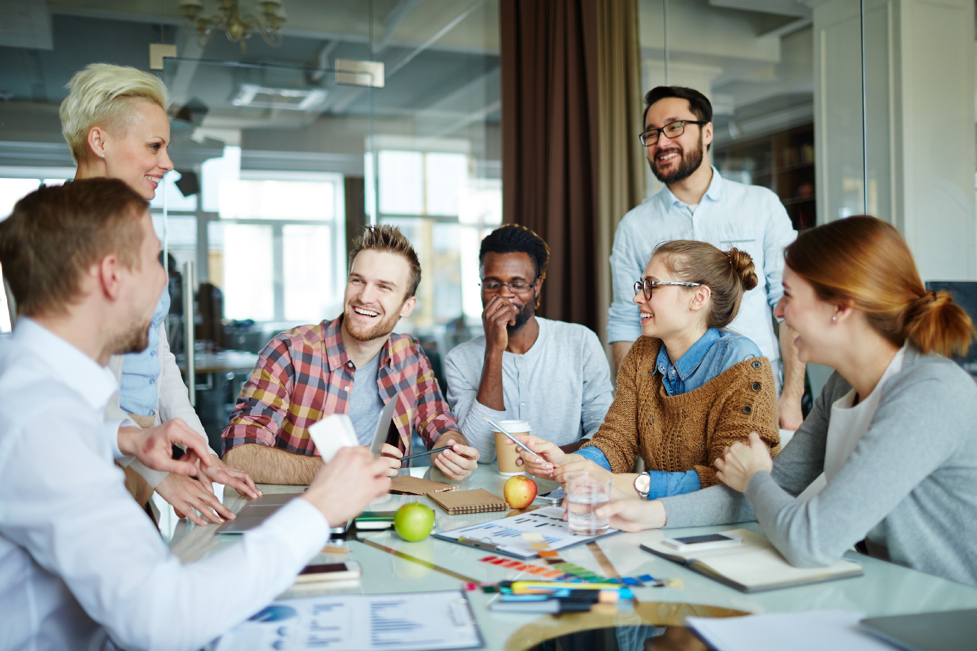 A diverse group of employees laughing together in a conference room. 