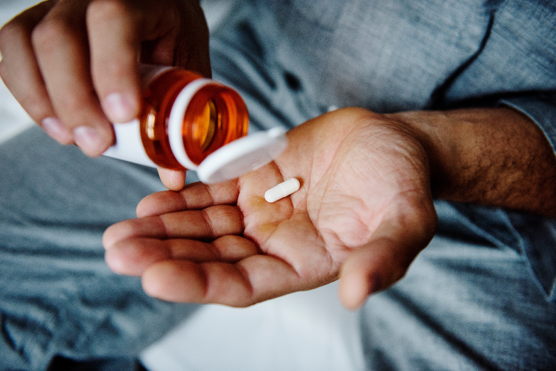  A middle aged man takes specialty prescription while sitting on a sofa.