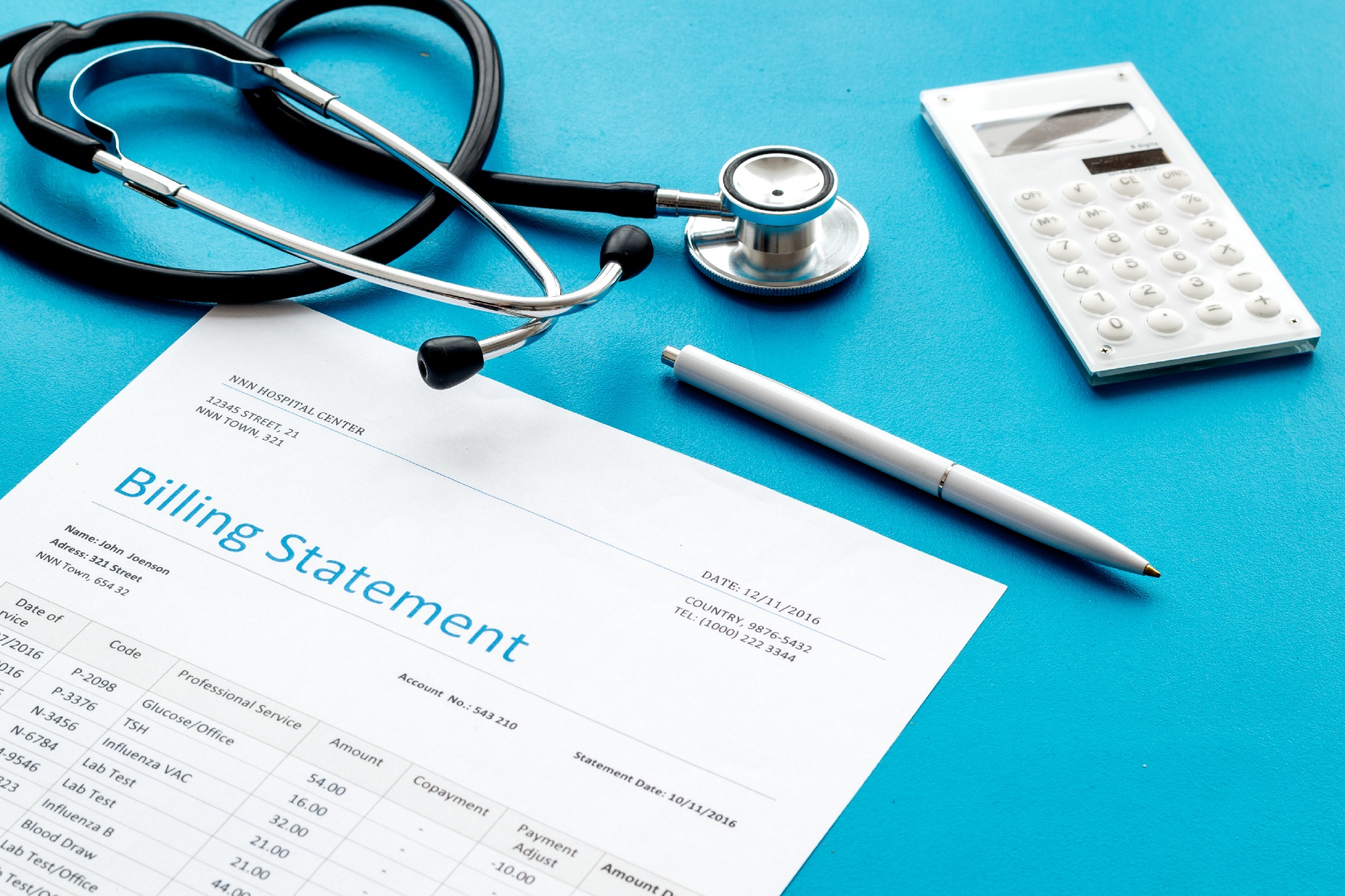 A medical bill, a stethoscope, and a calcuculator laying down on a table. 