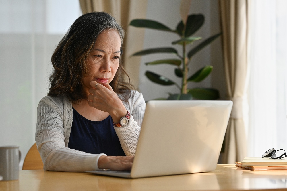 An older woman uses a laptop to access her Healthcare Bluebook account.