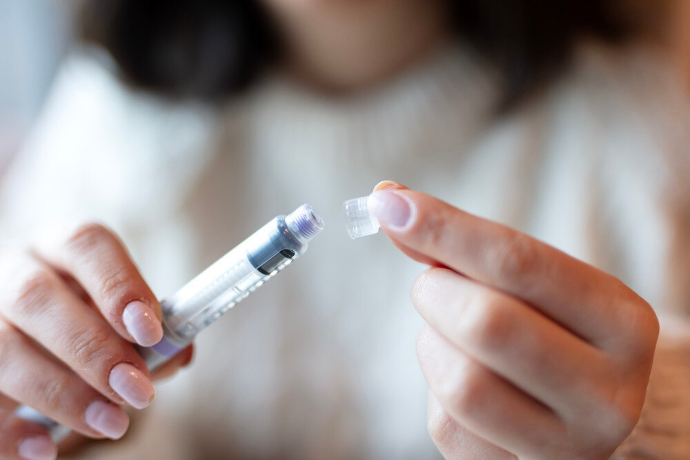 A female patient holds a GLP-1 injection.