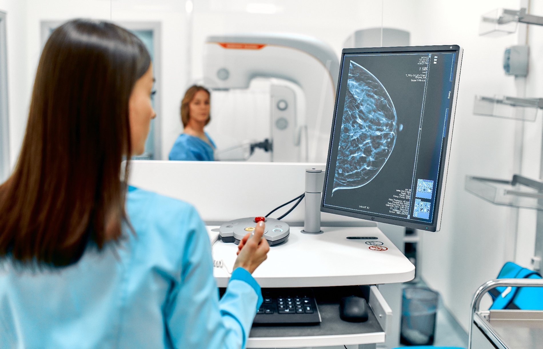 A female nurse helps a female patient during a mammogram. 